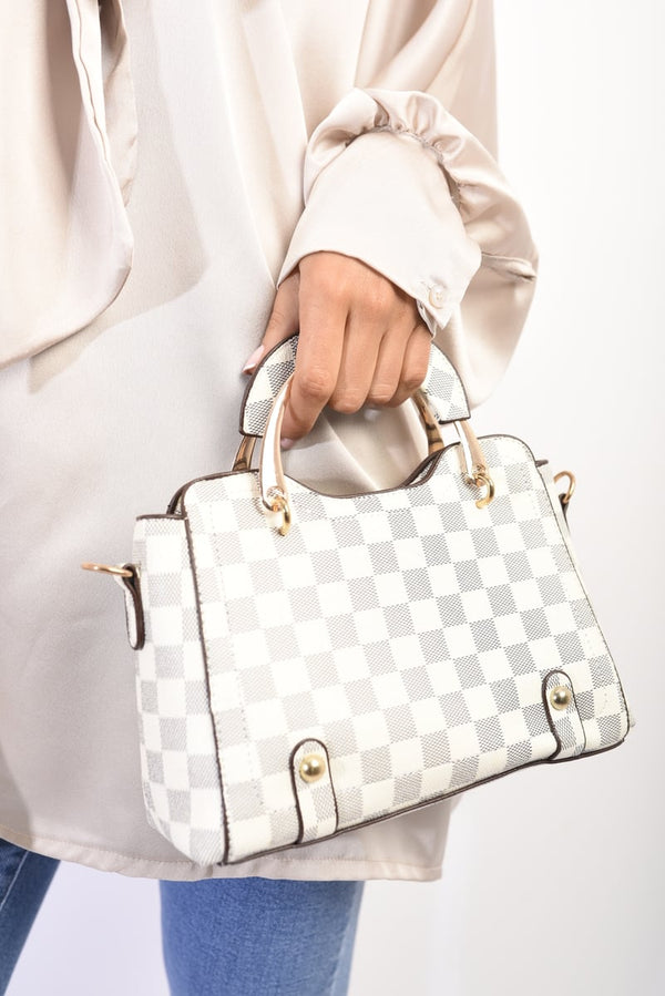 Hand holding Abby Grab Handles Shoulder Cross Body Handbag, a white and black checkered purse with versatile carrying options and practical compartments for stylish everyday use.