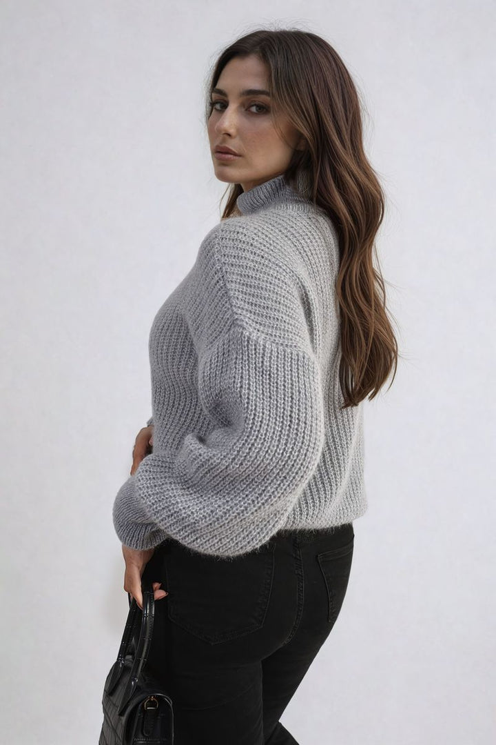 Woman in a chunky knit top with button details, holding a black bag, showcasing the cozy Alejandra Buttons Long Sleeves Chunky Knit Top.