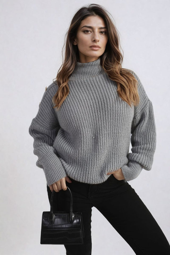 Woman in a chunky knit top holds a black purse, showcasing the Alejandra Buttons Long Sleeves Chunky Knit Top with button details.