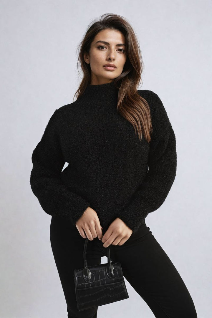 Woman in a black sweater holding a black purse, showcasing the Alejandra Buttons Long Sleeves Chunky Knit Top, ideal for stylish comfort and layering.