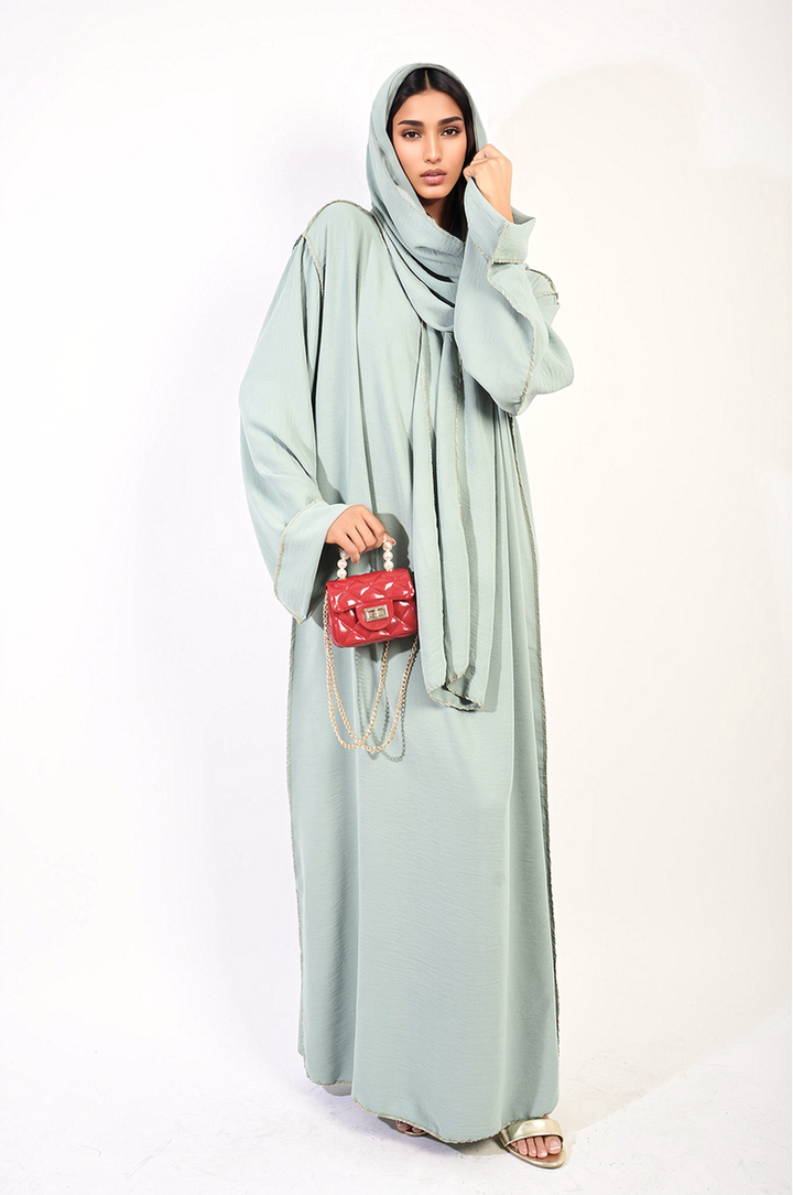 Woman holding Long Sleeve Closed Abaya Maxi Dress with Embellished Piping and red purse, showcasing the dress's elegant design and detailing.