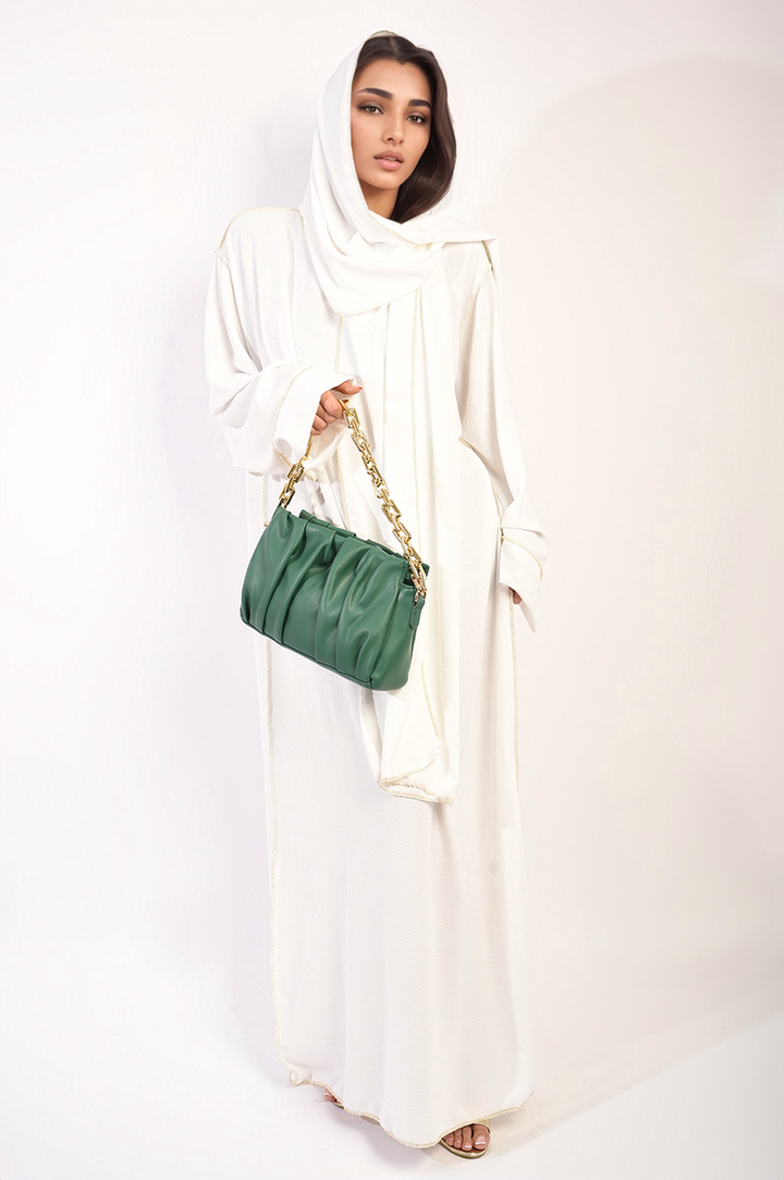 Woman in a white dress holding a Long Sleeve Closed Abaya Maxi Dress with Embellished Piping, showcasing its elegant style and gold chain accessory.