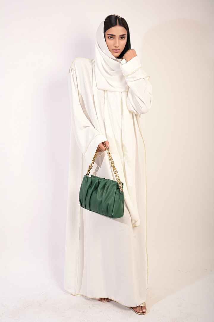 Woman in white dress holding Long Sleeve Closed Abaya Maxi Dress with Embellished Piping and green purse with gold chain.