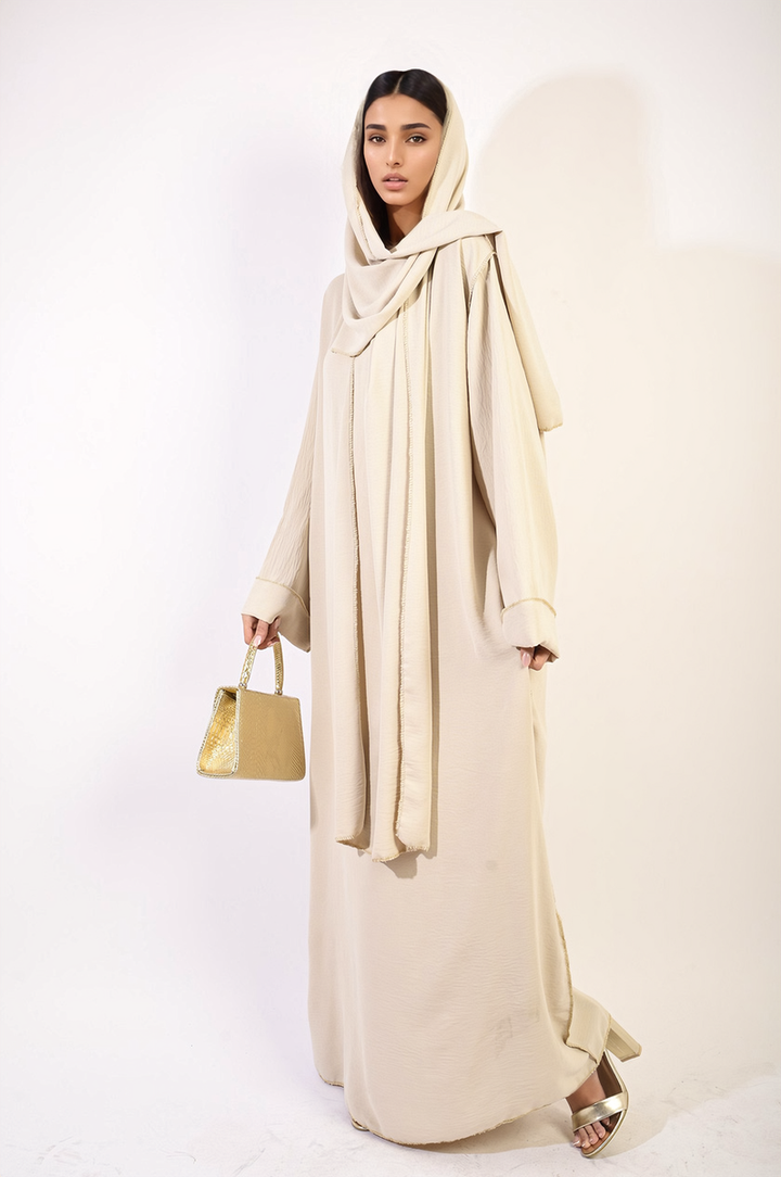 Woman wearing the Long Sleeve Closed Abaya Maxi Dress with Embellished Piping, holding a gold purse, showcasing elegance and modesty in design.