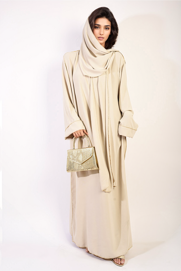 Long Sleeve Closed Abaya Maxi Dress With Embellished Piping, featuring a woman wearing the dress, holding a gold purse, showcasing its elegant design and modest style.