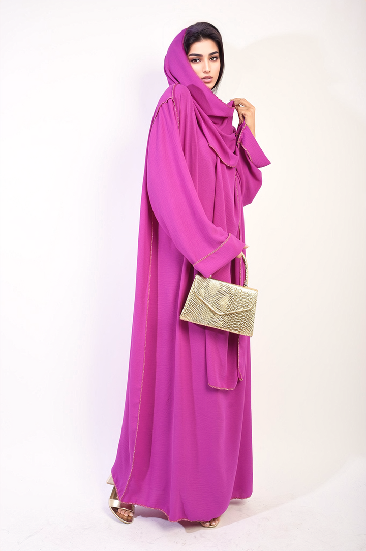 Long Sleeve Closed Abaya Maxi Dress with Embellished Piping worn by a woman holding a gold purse, complemented by a purple scarf.