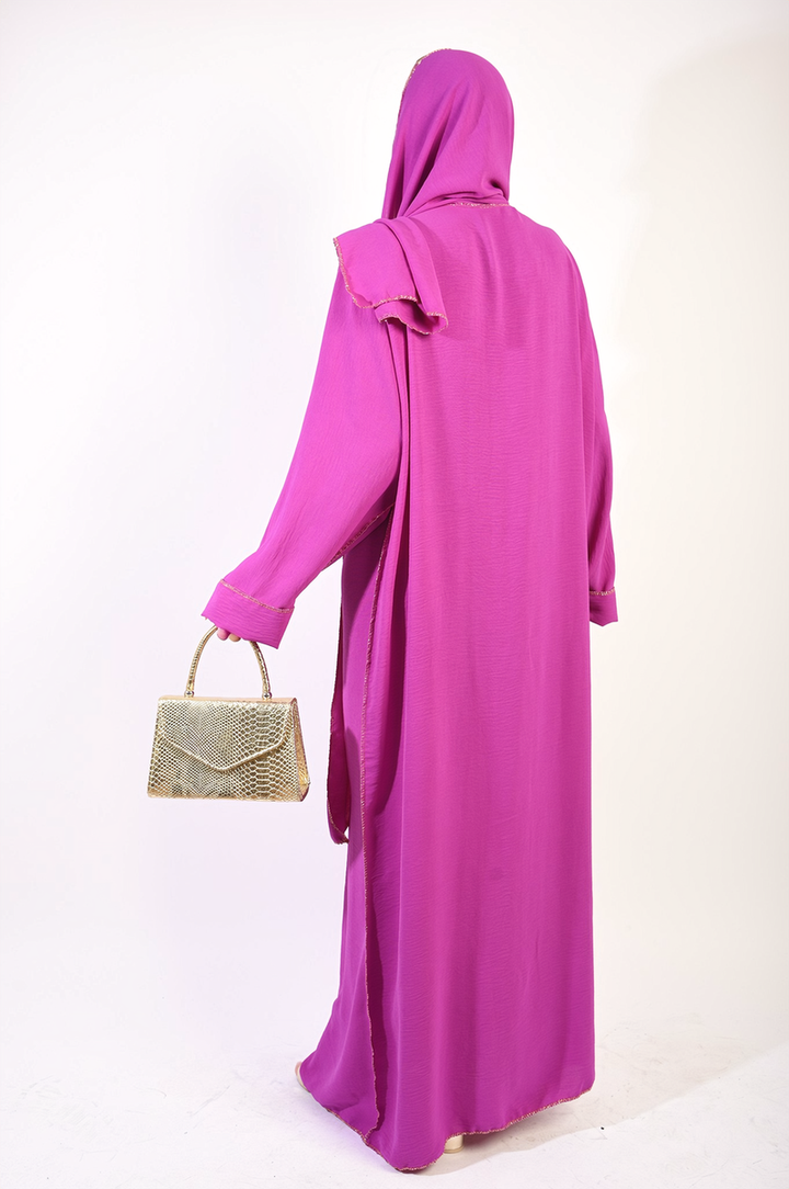 Woman holding a gold purse, wearing a Long Sleeve Closed Abaya Maxi Dress with Embellished Piping, showcasing its elegance and modest design.