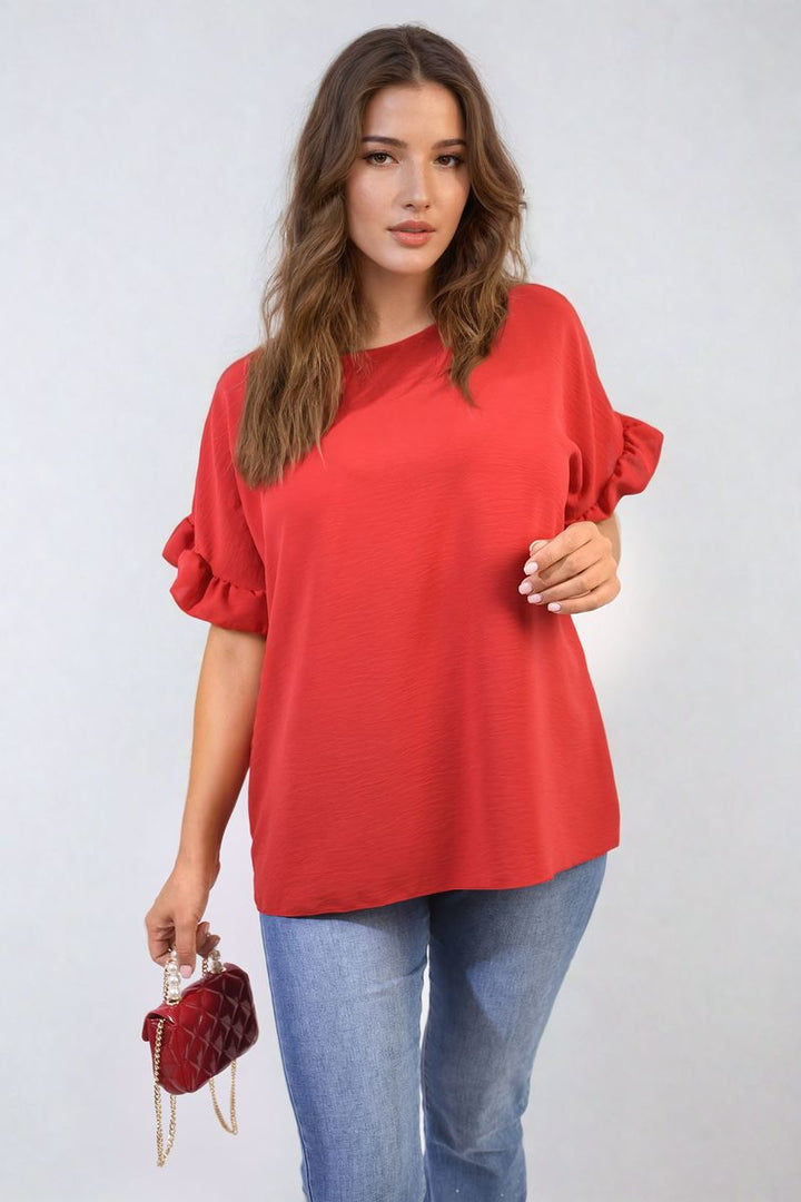 Woman wearing the Alexandra Frill Sleeve Top, holding a red purse, showcasing elegant frill sleeves perfect for versatile, stylish holiday or everyday outfits.