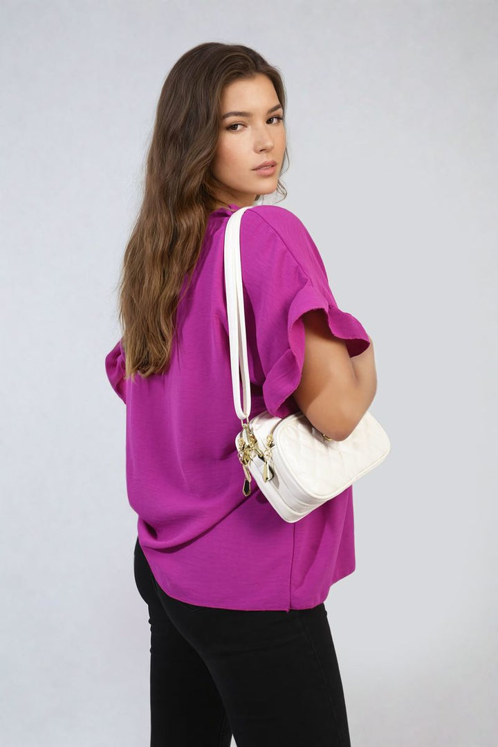 Woman wearing the Alexandra Frill Sleeve Top, holding a white purse. The top features elegant frill sleeves, ideal for versatile and stylish holiday wear.