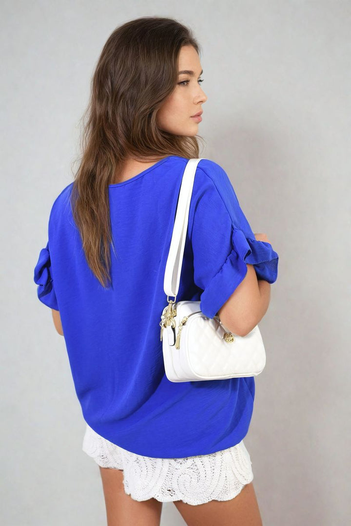 Woman wearing the Alexandra Frill Sleeve Top, holding a white purse, showcasing the top's elegant frill sleeves, ideal for stylish holiday and everyday outfits.