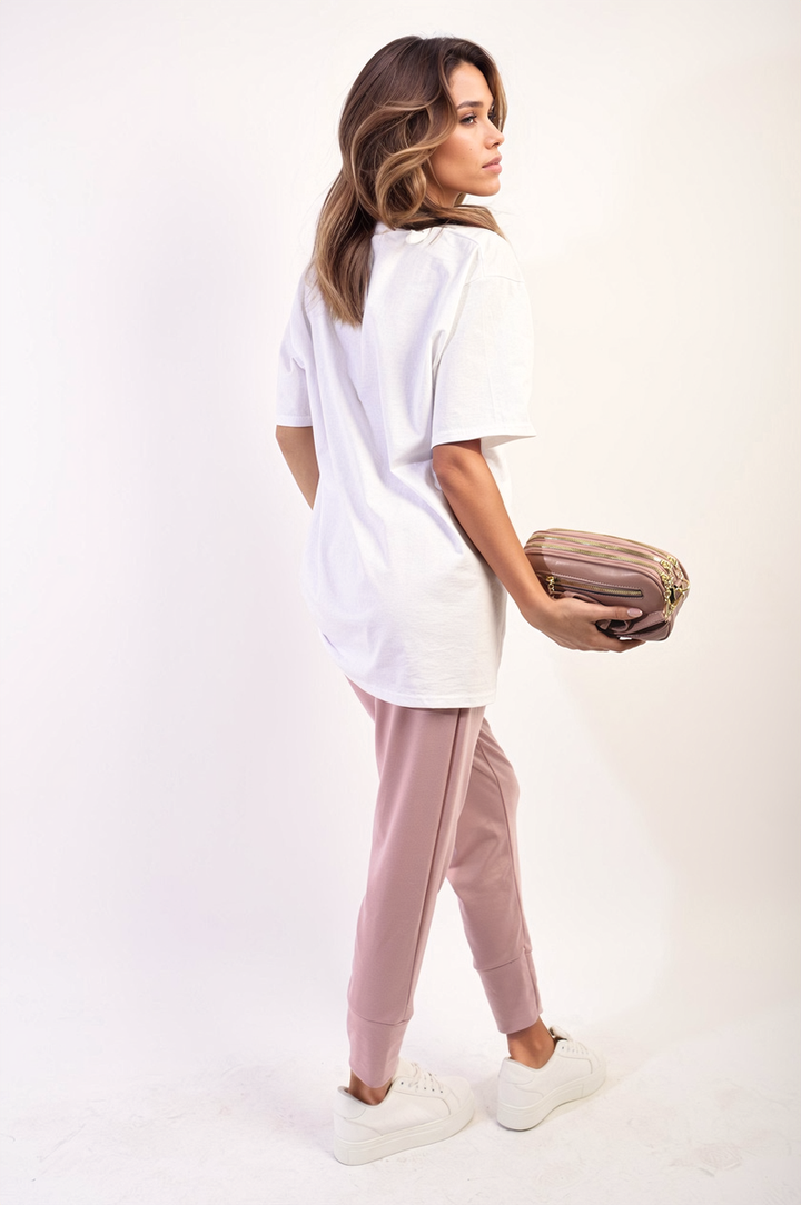 Woman wearing Oversized Love Slogan Print Top, holding a purse, paired with pink pants and white shoes, showcasing a casual, stylish look.