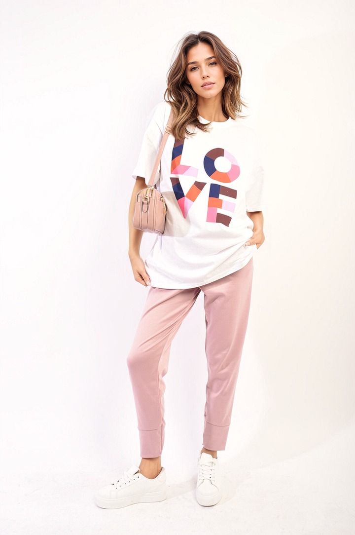 Woman wearing the Amanda Oversized Love Slogan Print Top, showcasing its relaxed fit and stylish design. Perfect for casual outings or lounging, offering comfort and fashion.