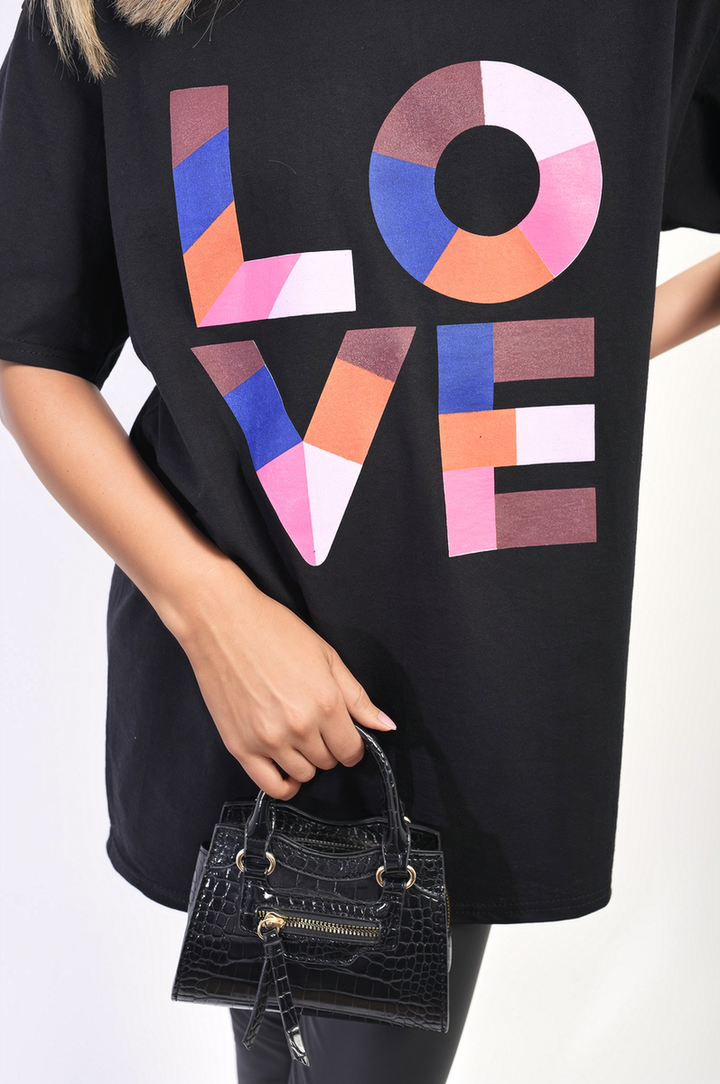 Person holding the Amanda Oversized Love Slogan Print Top, showcasing its vibrant design and relaxed fit, ideal for casual outings or laid-back days.