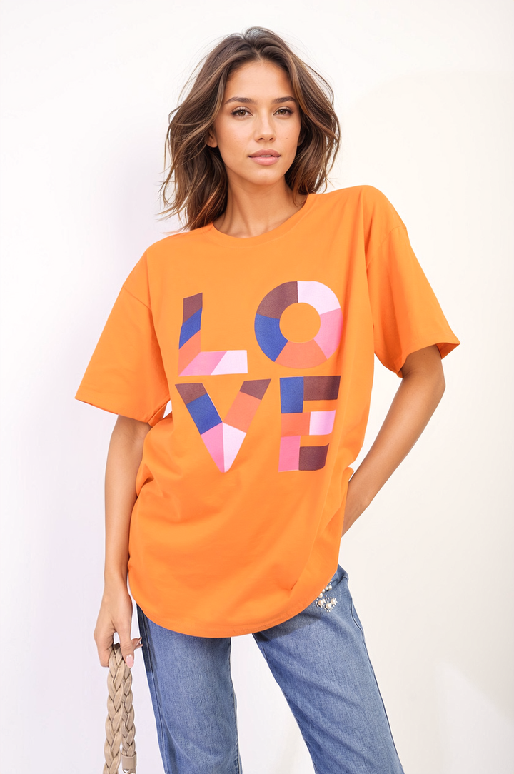 Woman wearing the Amanda Oversized Love Slogan Print Top, featuring a bold graphic design, paired with blue jeans for a casual, stylish look.