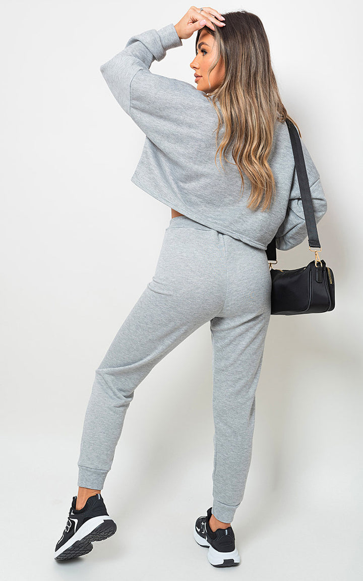 Woman in grey Sweatshirt and Jogger Loungewear Co-ord Set holding a black purse, showcasing stylish comfort and casual fashion.