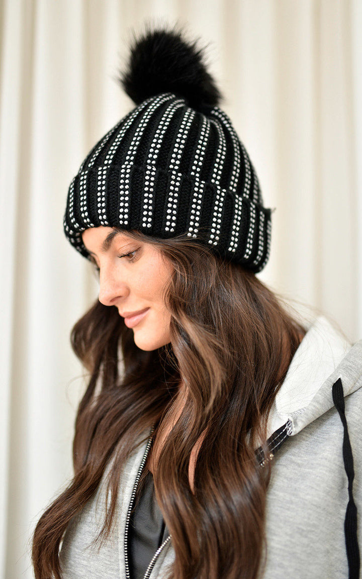 Woman wearing the Faux Fur Lined Beanie Rhine Stone Hat, showcasing its stylish design with rhinestone detail and faux fur lining for warmth.