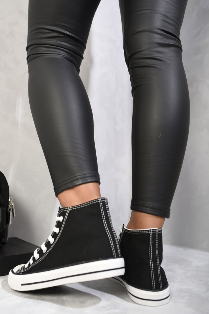 High Top Lace Up Trainers on legs in black leather pants, showcasing sleek design and high-top silhouette for style and ankle support.