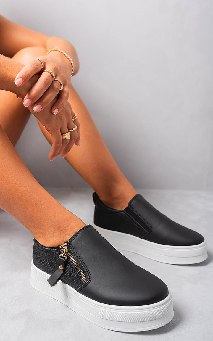 Andrea Zipper Decor Slip On Trainers featuring sleek silhouette and zipper accents, worn by a person, showcasing urban-chic style and effortless slip-on convenience.