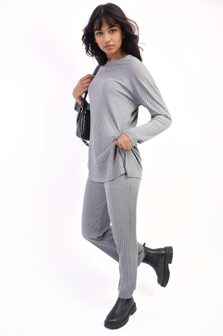 Woman wearing Annalise Knitted Top and Trouser Co-ord Set, paired with black boots and holding a small purse, showcasing a stylish, comfortable outfit.