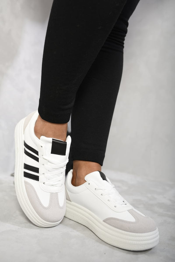 Striped Lace Up Trainers showcasing a bold striped design, perfect for casual outfits and adding a sporty vibe, depicted on a person wearing black pants.