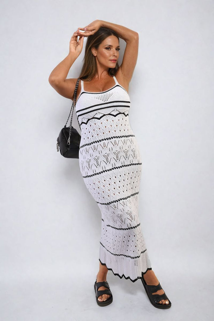 Woman in a Strappy Long Knitted Stripe Cami Dress holding a black purse, highlighting its elegant, flowing silhouette and modern style.