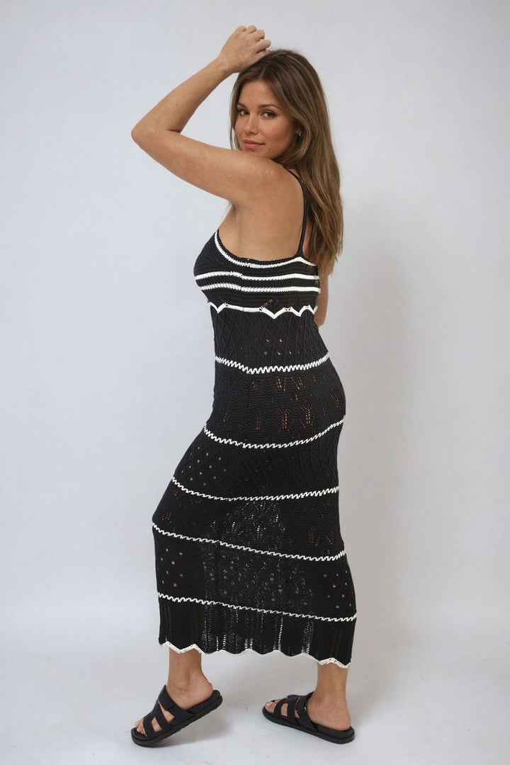 A woman models the Strappy Long Knitted Stripe Cami Dress, showcasing its elegant, flowing silhouette and modern strappy design.