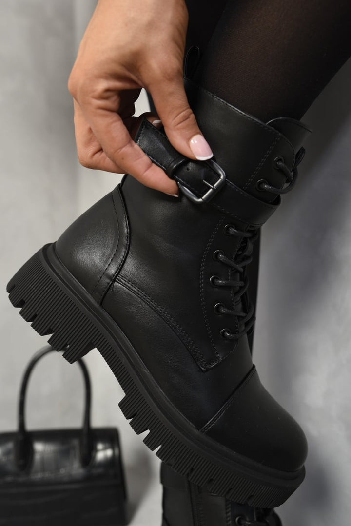 Person wearing Ariella Lace Up Buckle Chunky Combat Boots, highlighting lace-up front and buckle detailing, embodying a stylish, edgy vibe.