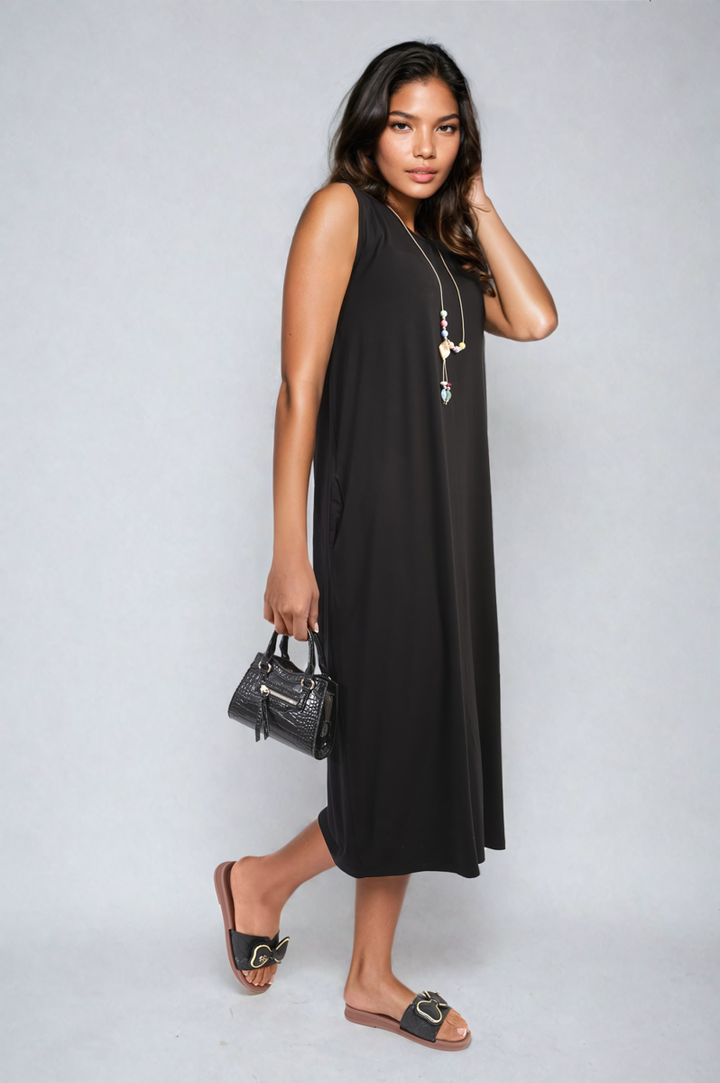 Woman wearing the Sleeveless Slit Midi Dress with Side Pockets, paired with sandals and holding a purse, showcasing its sleek design and practicality.