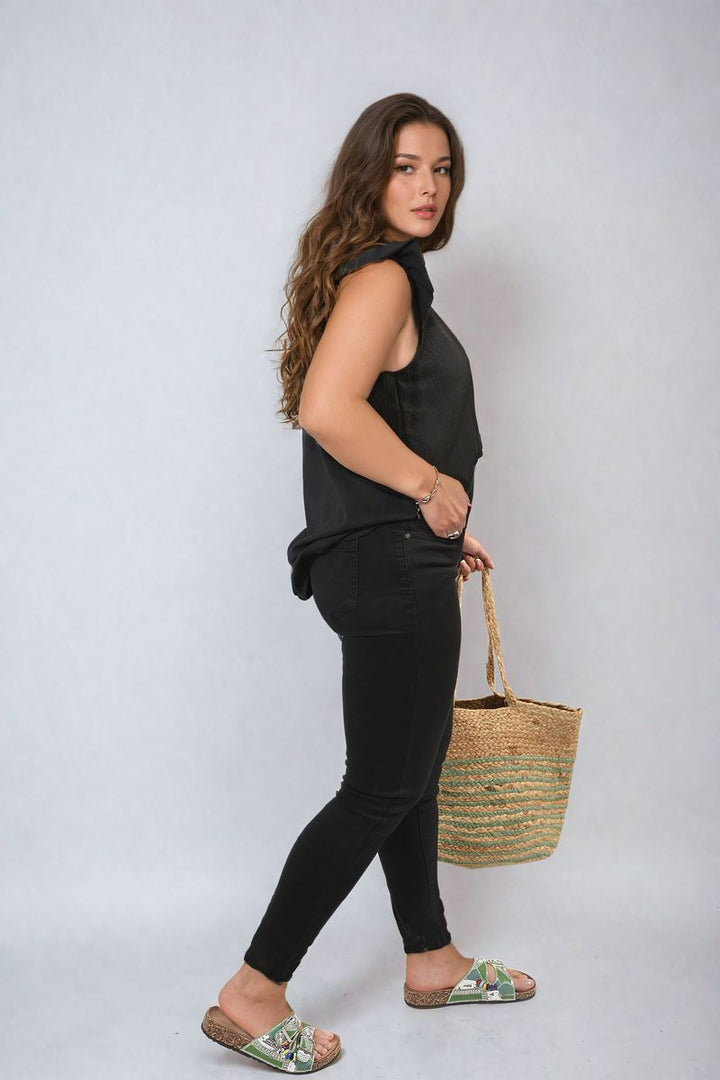 Woman wearing High Waist Distressed Hem Skinny Jeans with a straw bag and sandals, showcasing the jeans' high waist and distressed hem details.