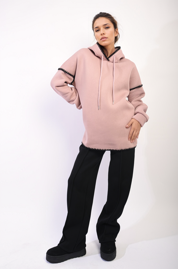 Woman wearing the Bella Blanket Stitch Knitted Hoodie, showcasing its cozy knit design and hood, ideal for casual outings or chilly days.