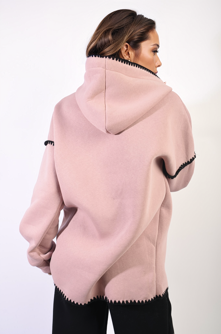 Woman wearing the Bella Blanket Stitch Knitted Hoodie, showcasing its cozy knit design and blanket stitch detail, perfect for style and comfort on chilly days.