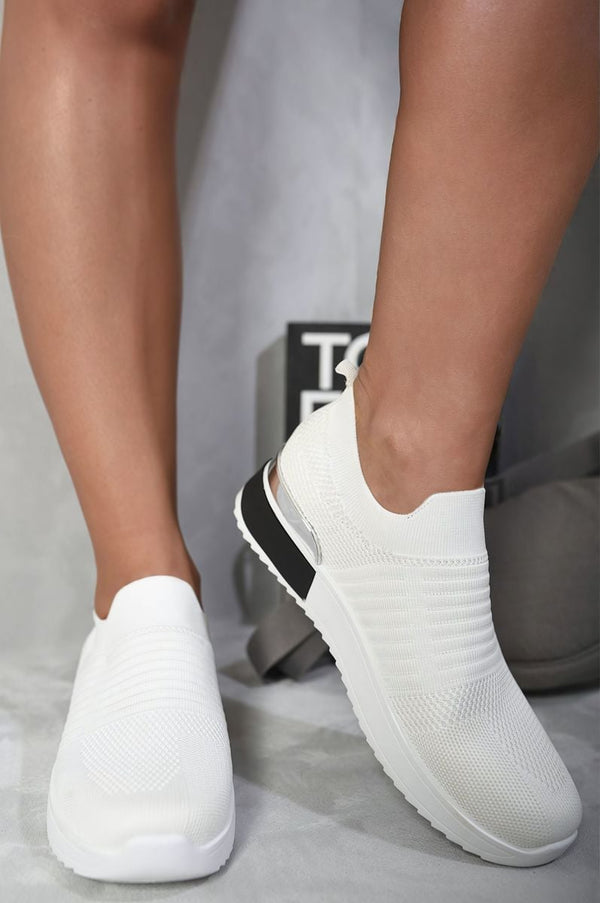 White Slip On Sock Wedge Trainers on a person's feet, showcasing their comfortable sock-like fit and stylish wedge design, ideal for casual outings.