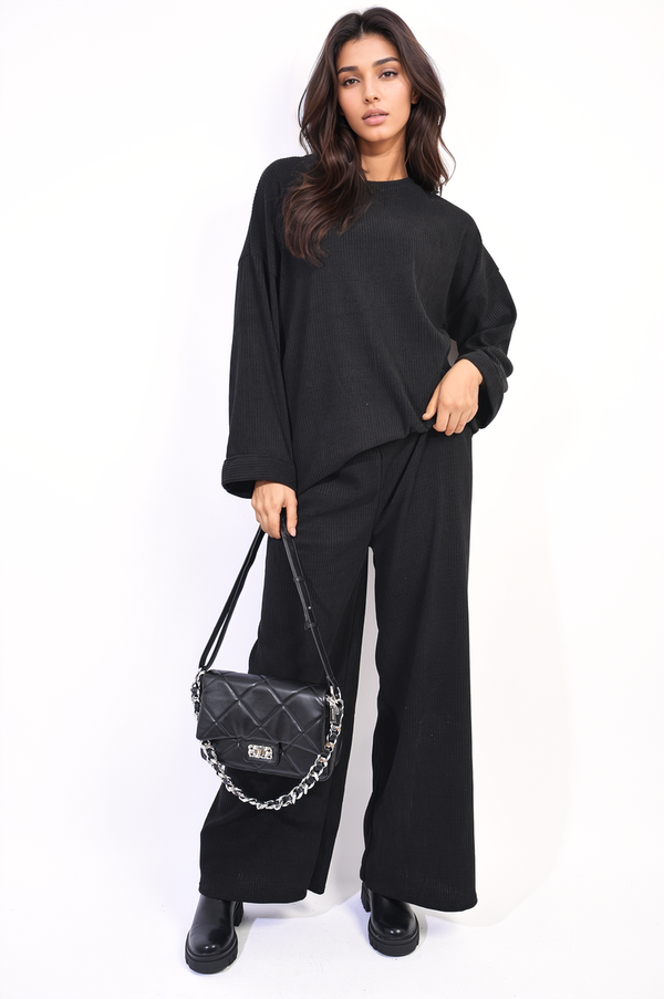 Woman wearing the Bianca Loose Long Sleeve Top and Wide Leg Trousers Co-ord Set, holding a black purse, showcasing a sleek and stylish outfit.