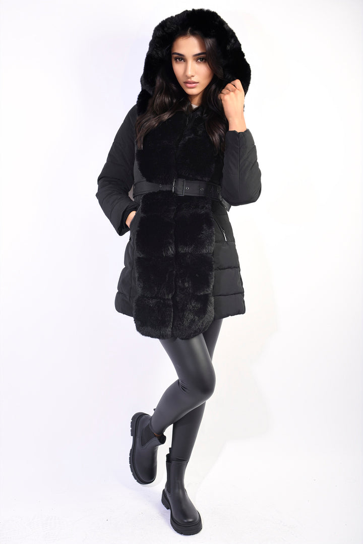 Woman wearing the Bridget Padded Faux Fur Trim Longline Coat, showcasing its longline style, faux fur hood, and boots, perfect for winter warmth and style.