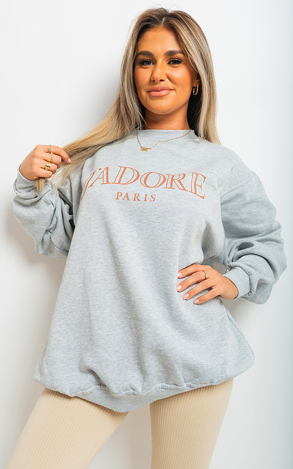 Woman wearing J'Adore Paris Print Oversized Jumper Top, showcasing its chic oversized fit and Parisian-inspired print, ideal for stylish, casual outings.