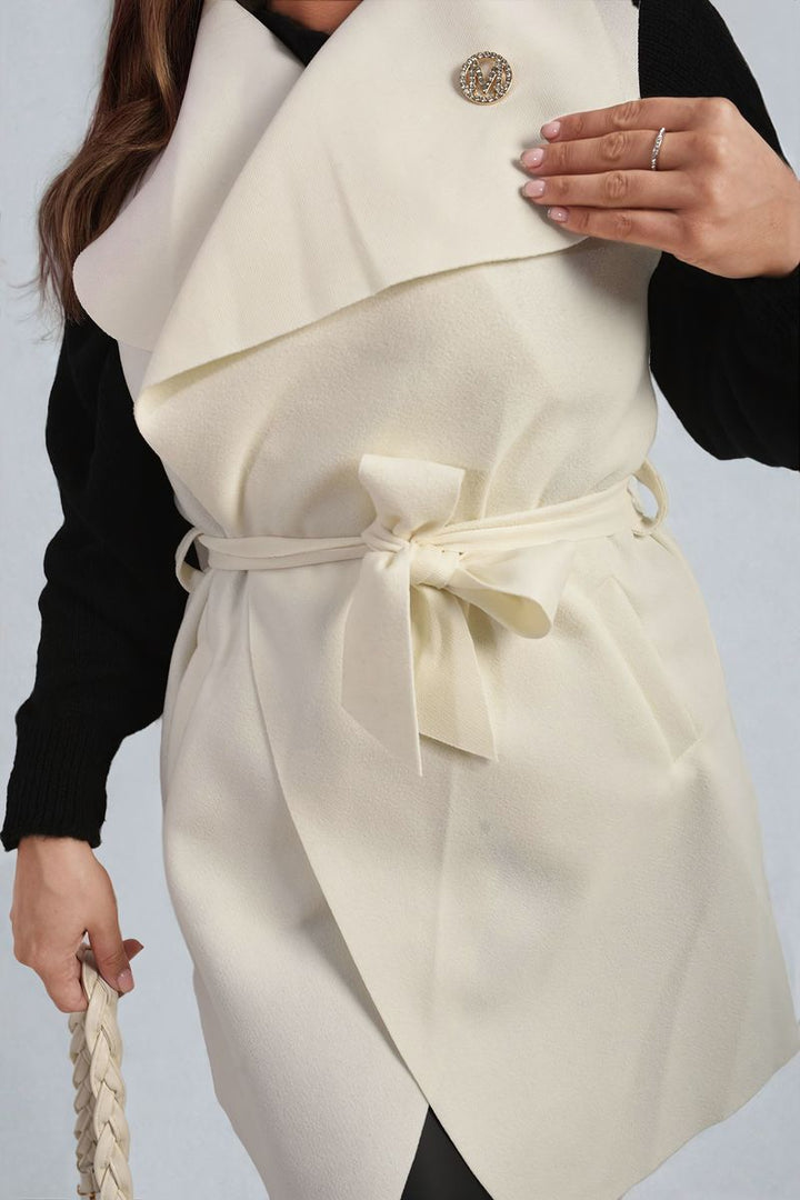 Woman wearing a Wide Lapel Sleeveless Belted Jacket, showcasing its stylish wide lapel and flattering belted waist, perfect for layering over tops.