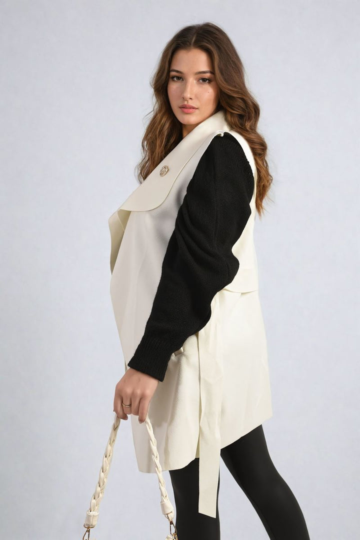 Woman wearing a Wide Lapel Sleeveless Belted Jacket, holding a white purse, showcasing a chic, stylish look perfect for layering and fashion versatility.