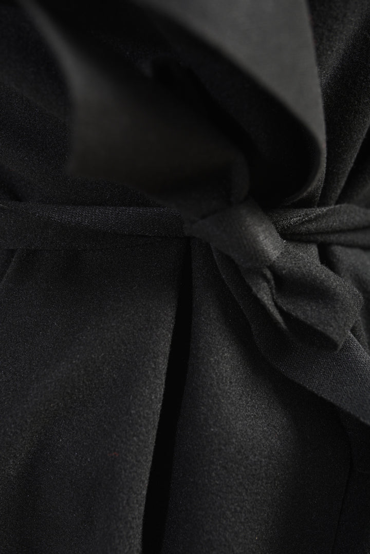 Close-up of the Wide Lapel Sleeveless Belted Jacket's black fabric, highlighting its sleek texture and stylish design, perfect for layering and creating a chic silhouette.