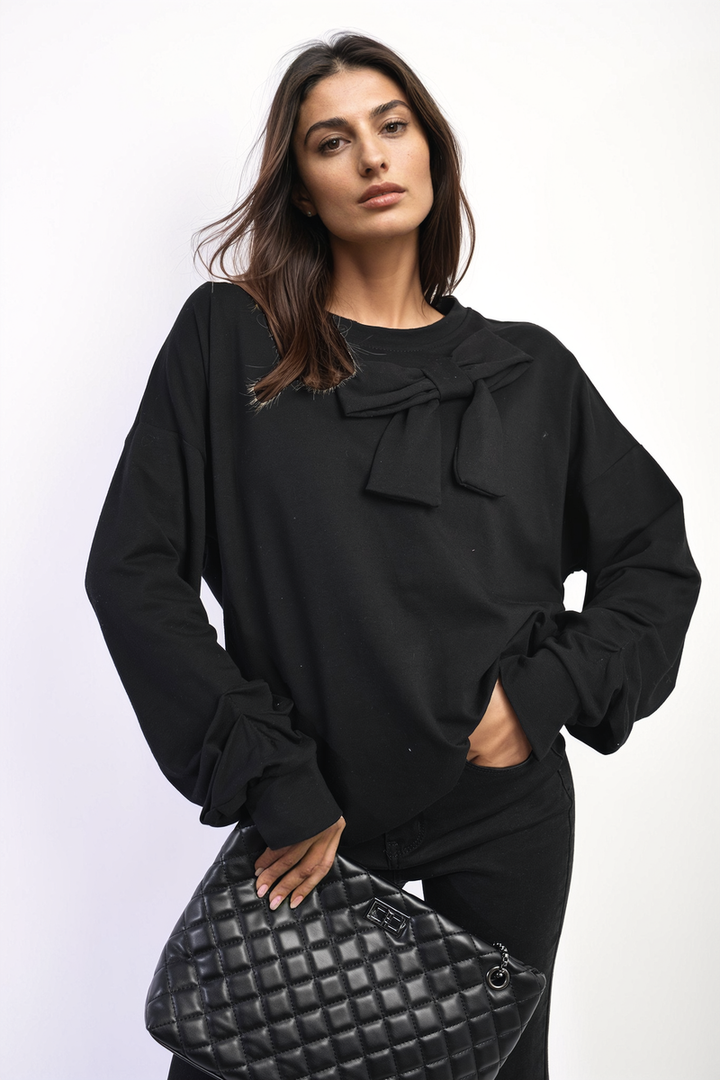 Woman wearing Long Sleeve Bow Detail Jumper, holding a black handbag; jumper features elegant bow detail on sleeves, showcasing stylish design ideal for everyday wear.