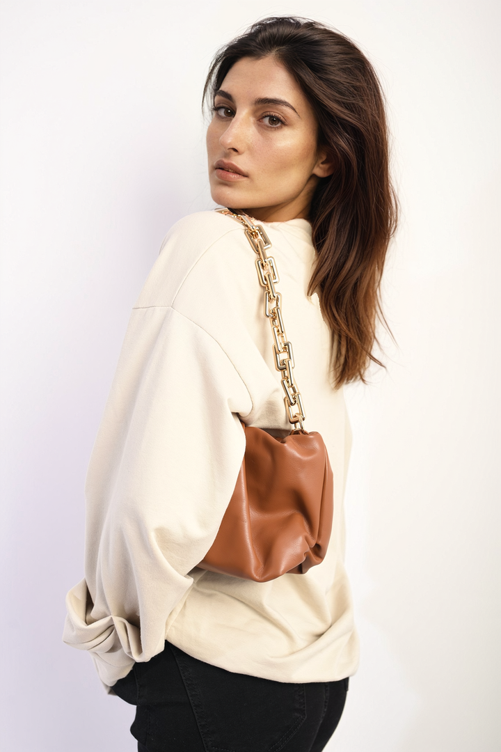 Woman wearing the Long Sleeve Bow Detail Jumper with a brown purse over her shoulder, showcasing elegant bow detail on the sleeves.