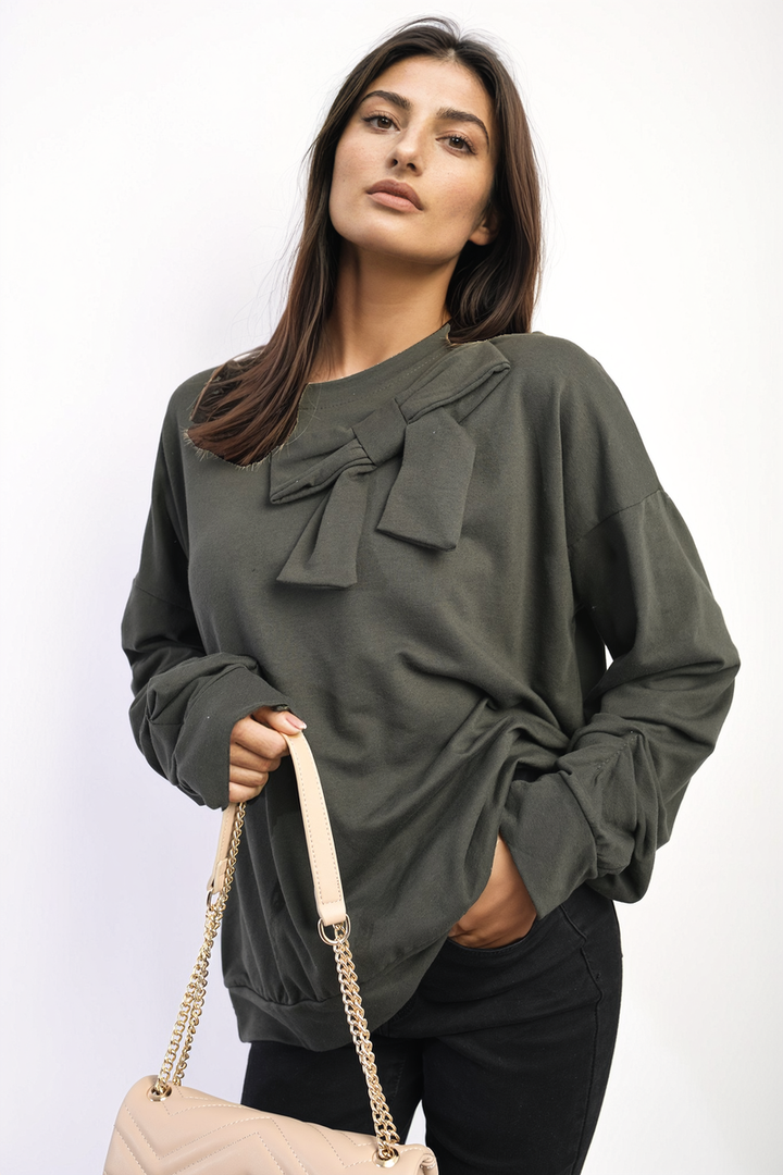 Woman showcasing the Carina Long Sleeve Bow Detail Jumper, holding a purse, highlighting the jumper's elegant bow details on the sleeves.