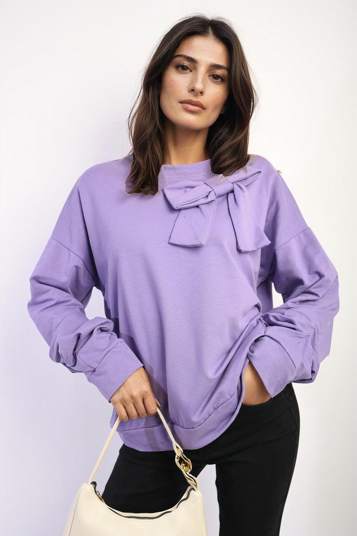 Woman in a purple Long Sleeve Bow Detail Jumper holding a white purse, showcasing the jumper's elegant bow detail on the sleeves.