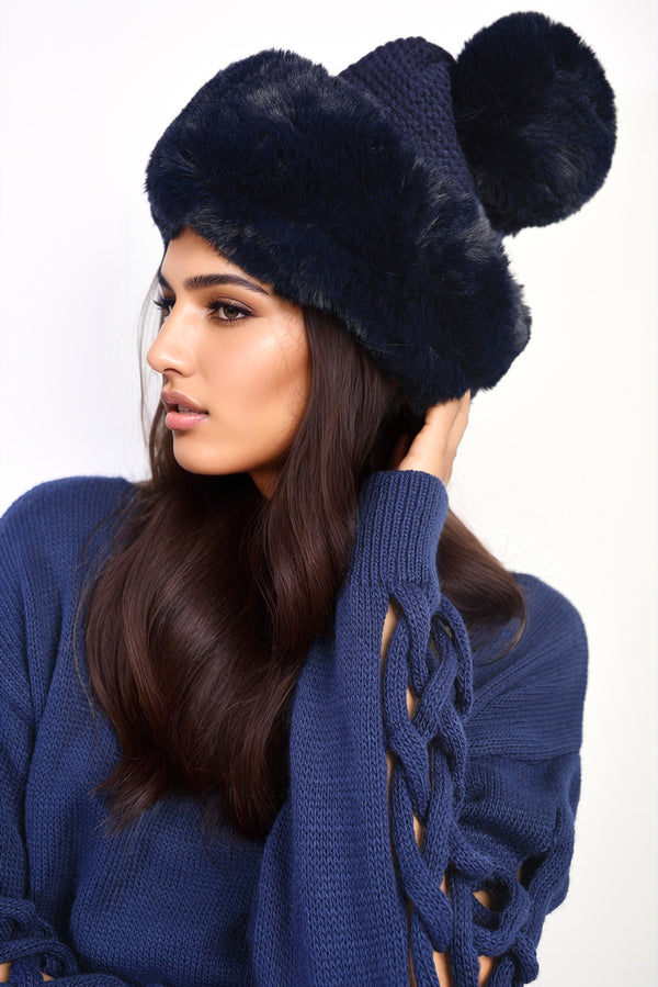 Woman wearing the Carly Faux Fur Knitted Winter Hat, featuring a chic knitted exterior and playful pom-pom, ideal for stylish warmth during winter.