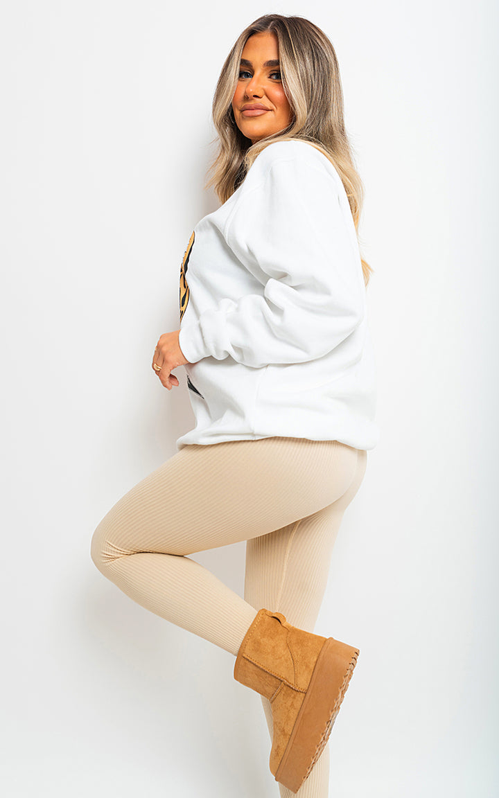 Woman wearing Wild Thang Tiger Print Knitted Jumper, posing in tights and white sweatshirt, showcasing the bold design and cozy fit for stylish versatility.