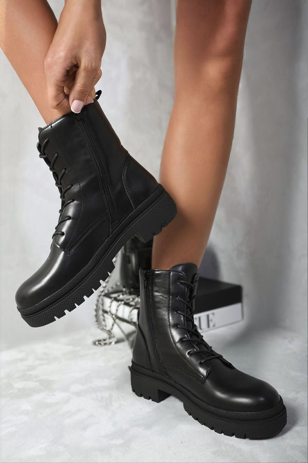 Person wearing Carmen Lace Up Side Zip Chunky Ankle Boots, showcasing the stylish lace-up front and side zip design, perfect for adding edge to any outfit.