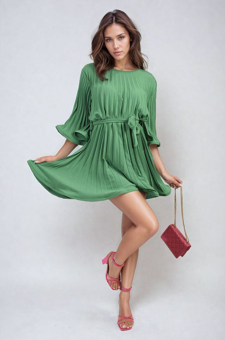 Woman in green Pleated Tie Waist Mini Dress holding a pink purse with gold chain, showcasing chic and elegant fashion from Holiday Clothes UK.