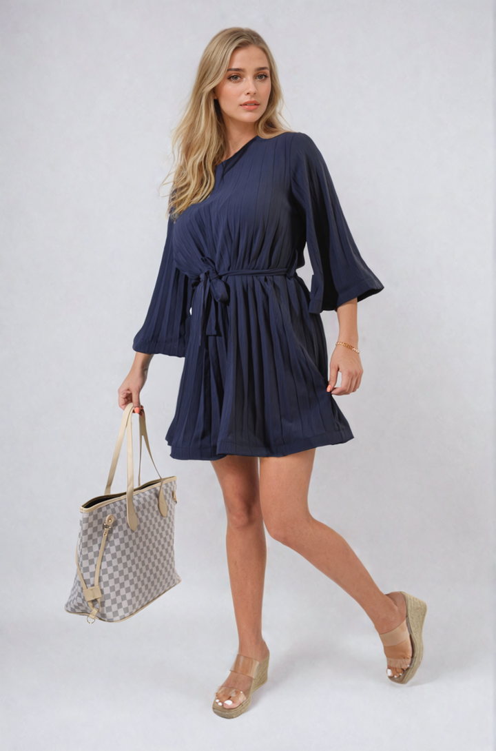 Woman in a blue Pleated Tie Waist Mini Dress holding a purse, showcasing elegant pleating and a flattering tie waist design, perfect for stylish occasions.