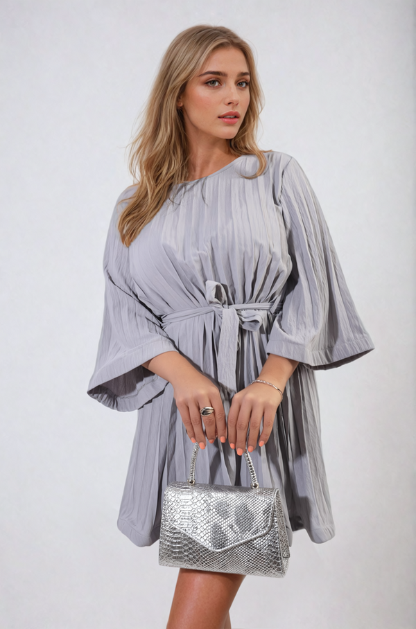 Pleated Tie Waist Mini Dress worn by a woman holding a purse, showcasing its elegant pleating and flattering silhouette. Ideal for stylish holiday or everyday wear.