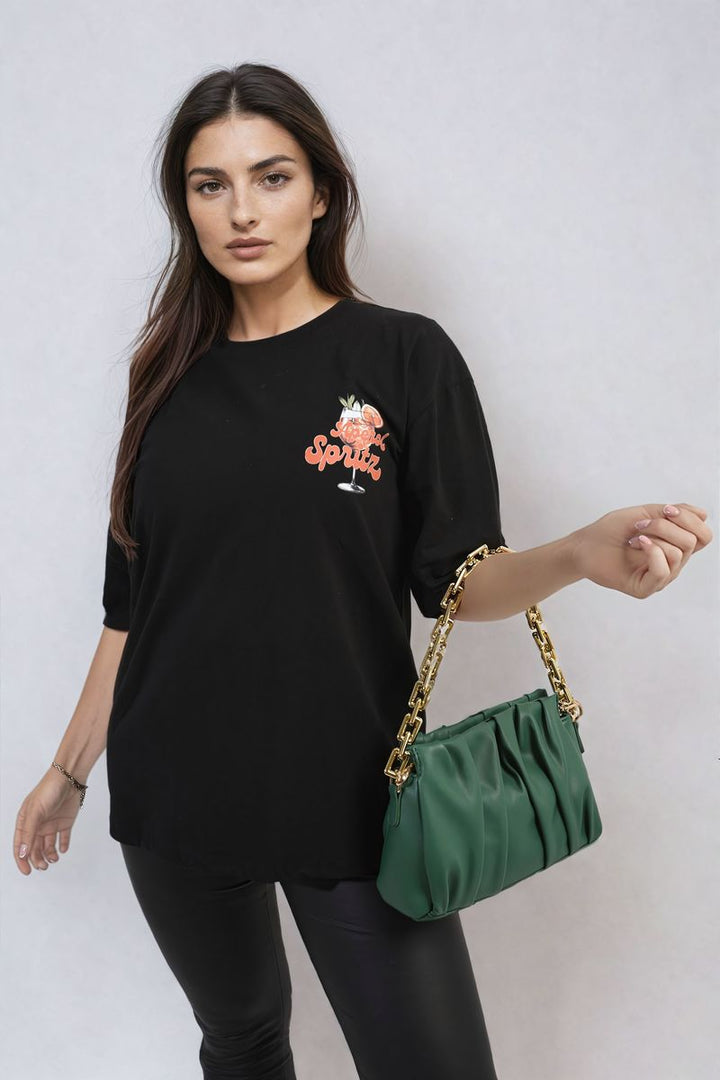 Woman wearing Aperol Spritz Cocktail Graphic Top, holding a green purse, capturing a laid-back, stylish vibe for holiday wear from Holiday Clothes UK.