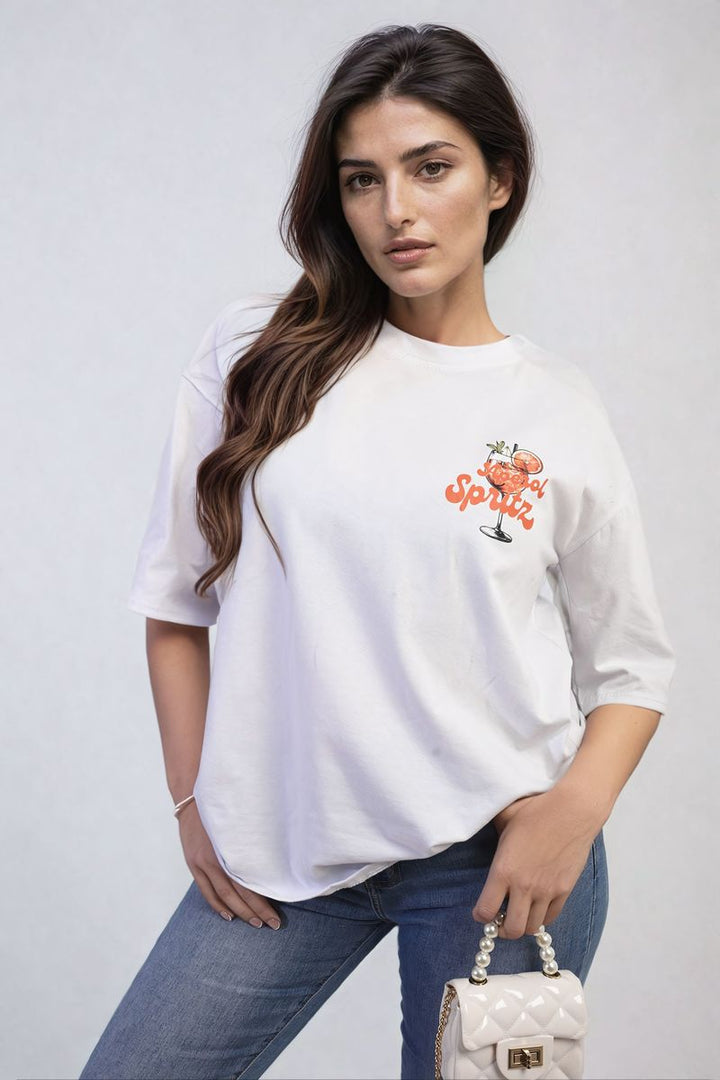 Woman wearing the Aperol Spritz Cocktail Graphic Top, posing casually, exemplifying a relaxed, stylish vibe perfect for summer outings and beach days.